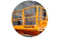 Un elevador aéreo Haulotte amarillo está estacionado en un almacén.