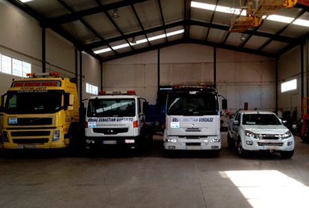 Una fila de camiones y coches están estacionados en un almacén.