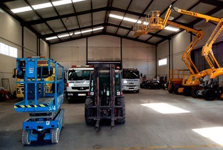 Un almacén lleno de mucha maquinaria, incluida una carretilla elevadora.