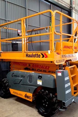 Un elevador de tijera amarillo está estacionado en un almacén.