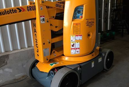 Un elevador aéreo amarillo está estacionado en un garaje.