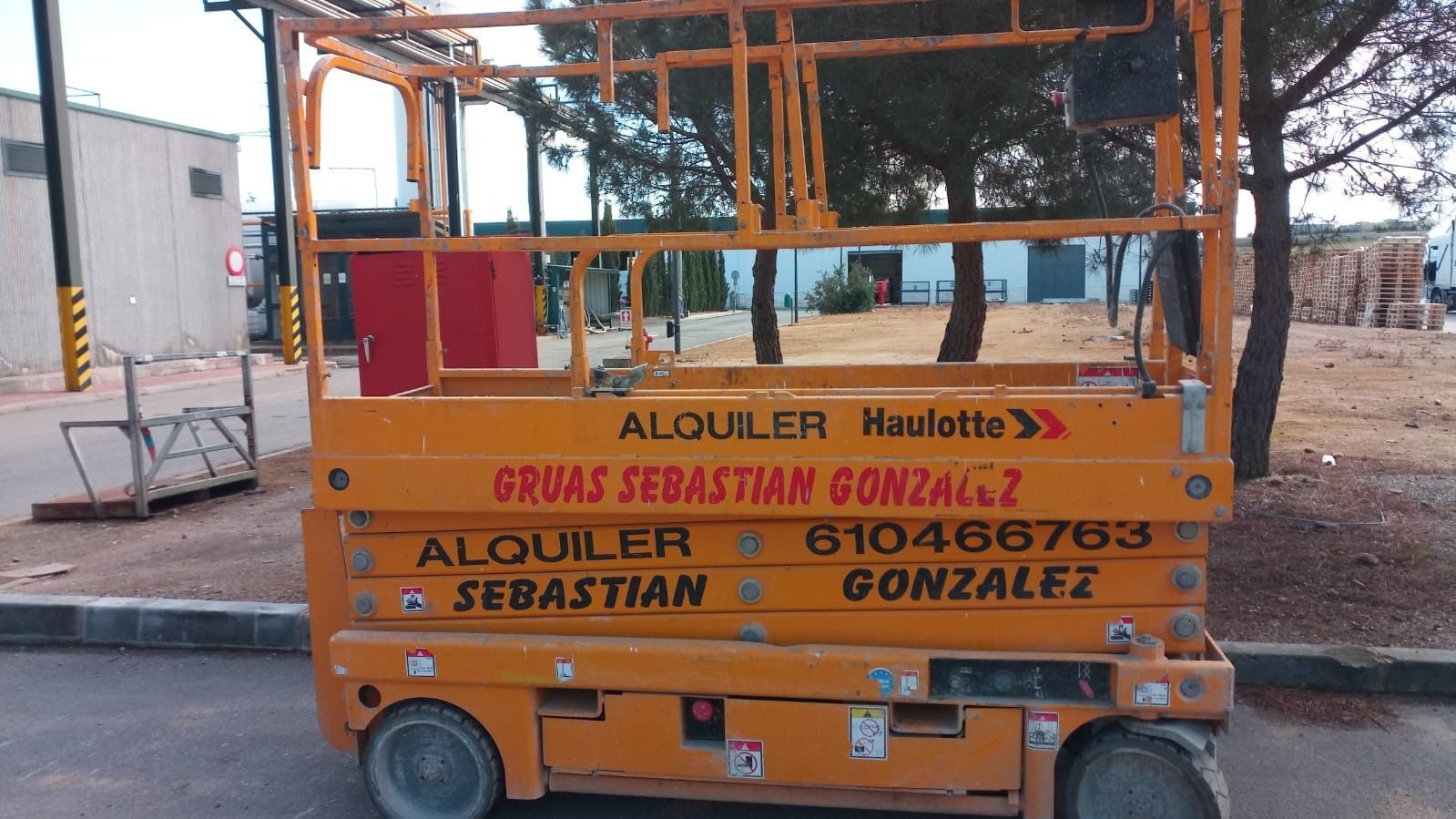 Un elevador de tijera naranja está estacionado al costado de la carretera