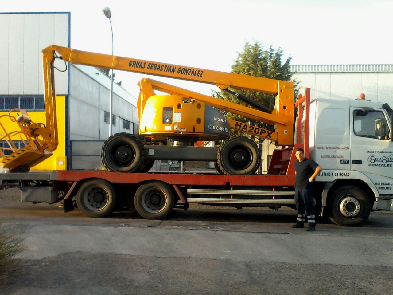 Un hombre de pie junto a un camión con un elevador en la parte trasera.