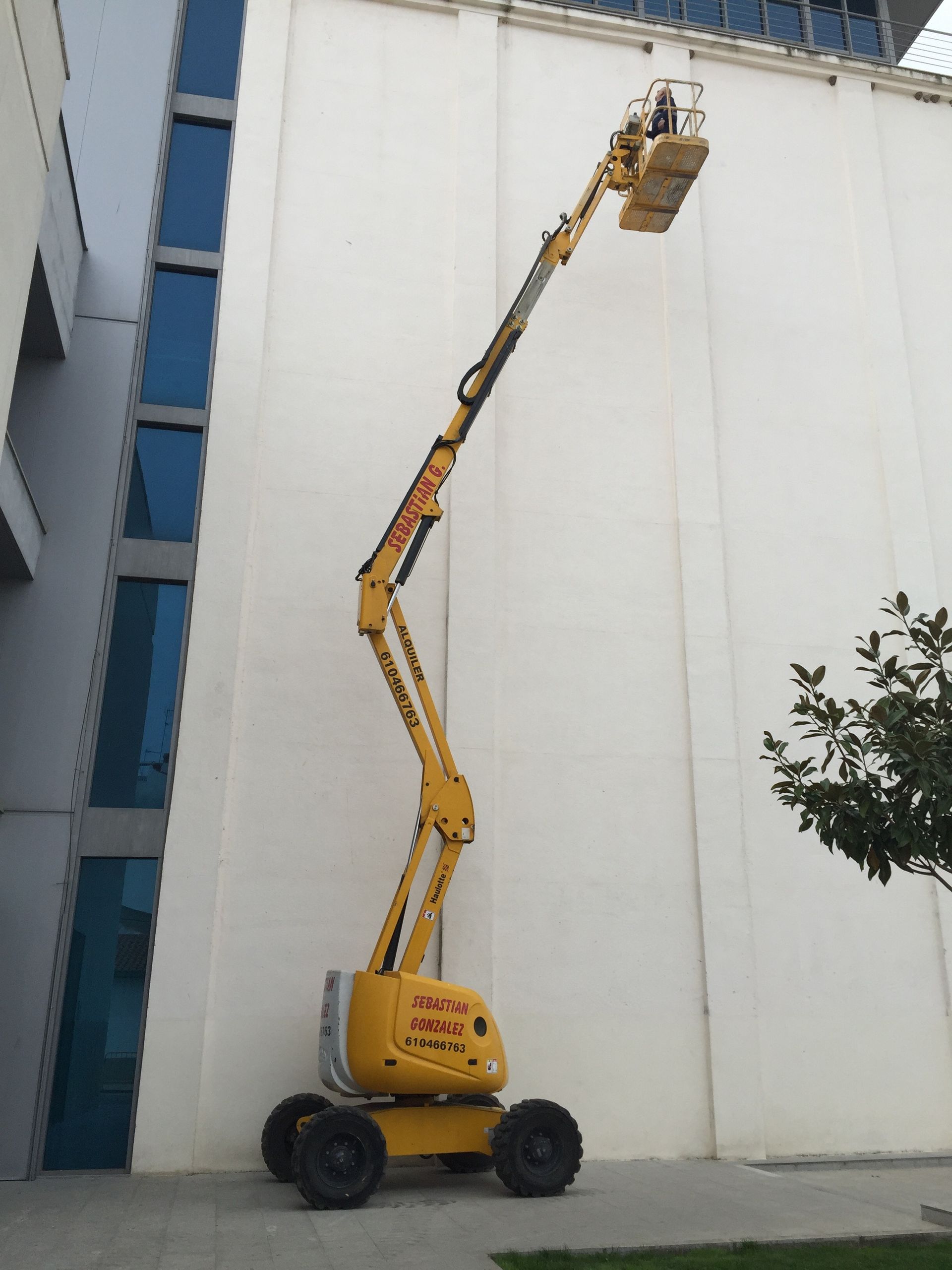Un elevador aéreo amarillo está estacionado frente a un edificio