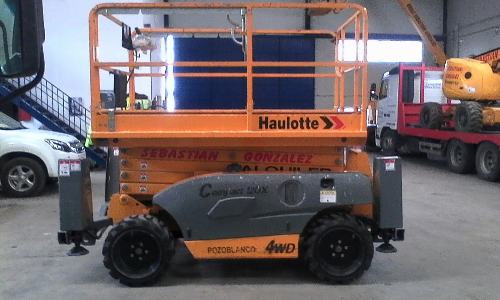 Un vehículo Haulotte amarillo está estacionado en un almacén.