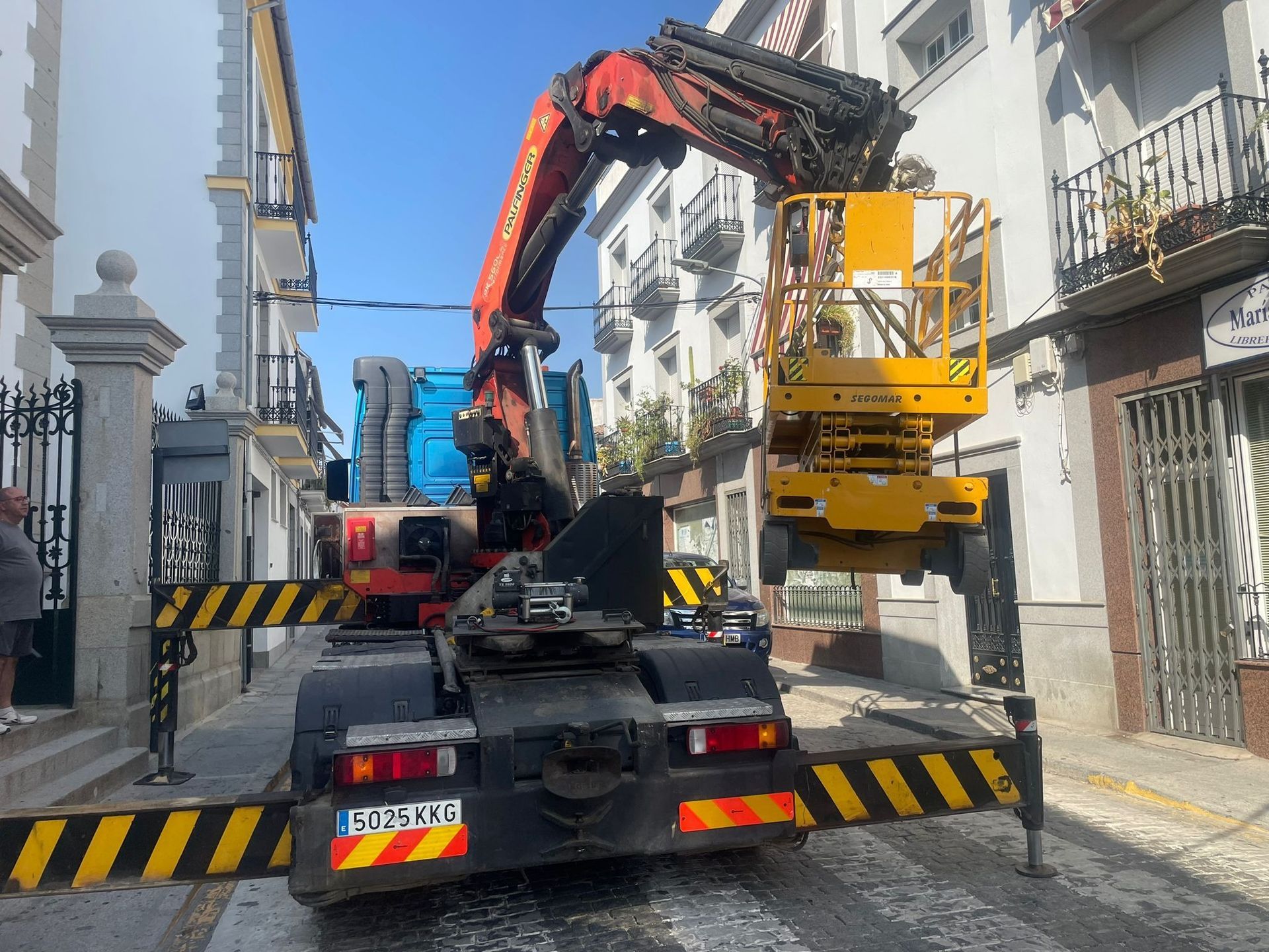 Una grúa está fijada a la parte trasera de un camión en una calle de la ciudad.