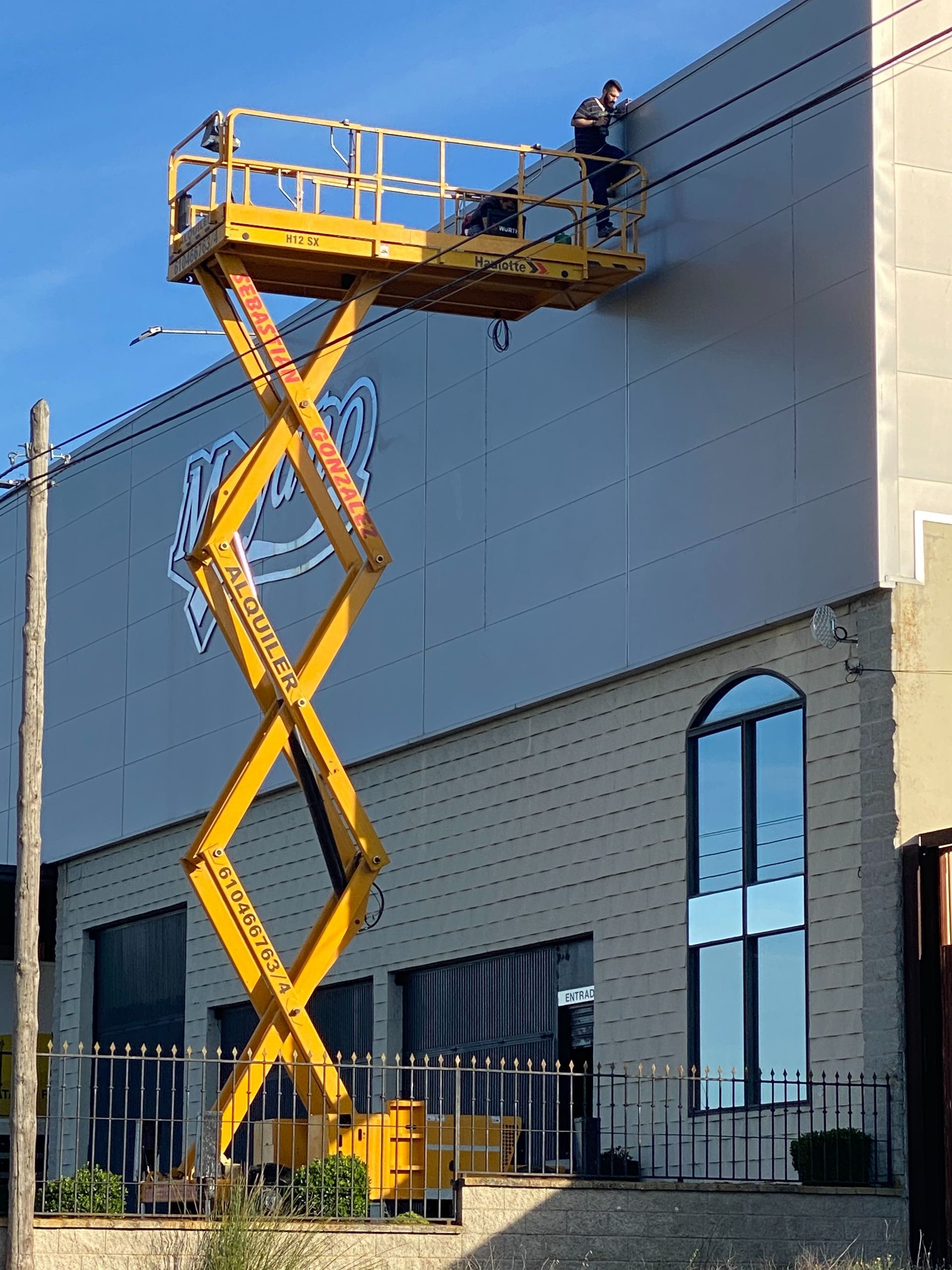 Se está utilizando un elevador de tijera amarillo para pintar un edificio