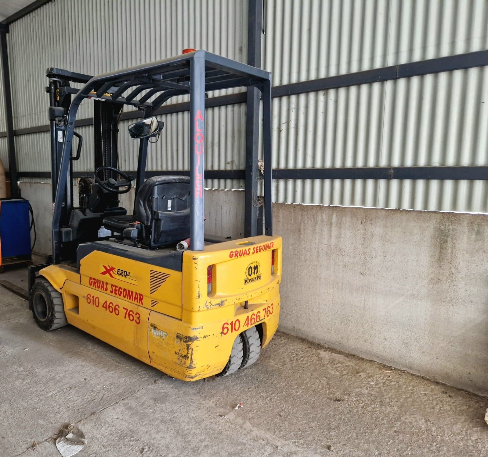 Una carretilla elevadora amarilla está estacionada frente a una pared