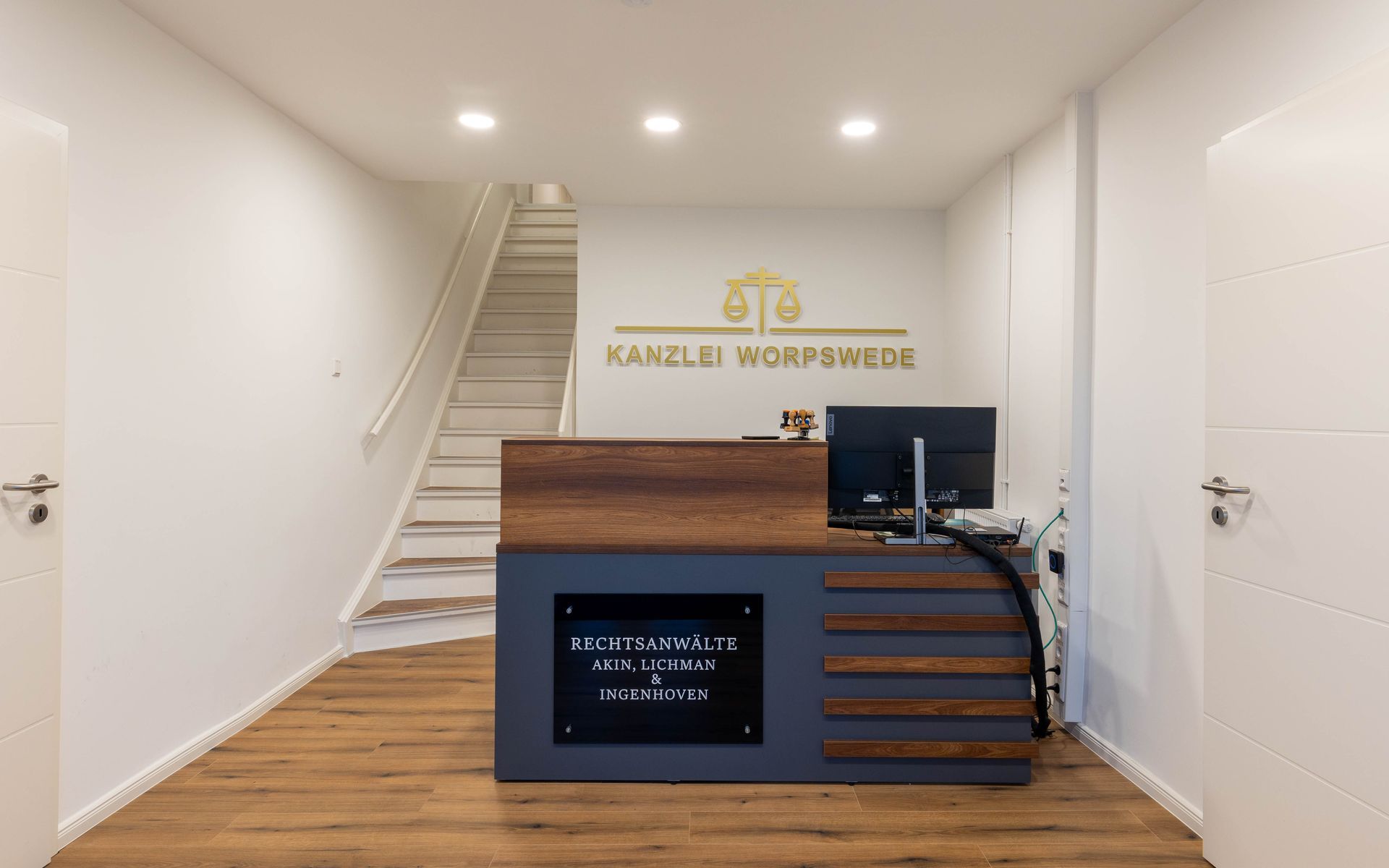 Eine Rezeption in einem Flur, zu dem eine Treppe hinaufführt.