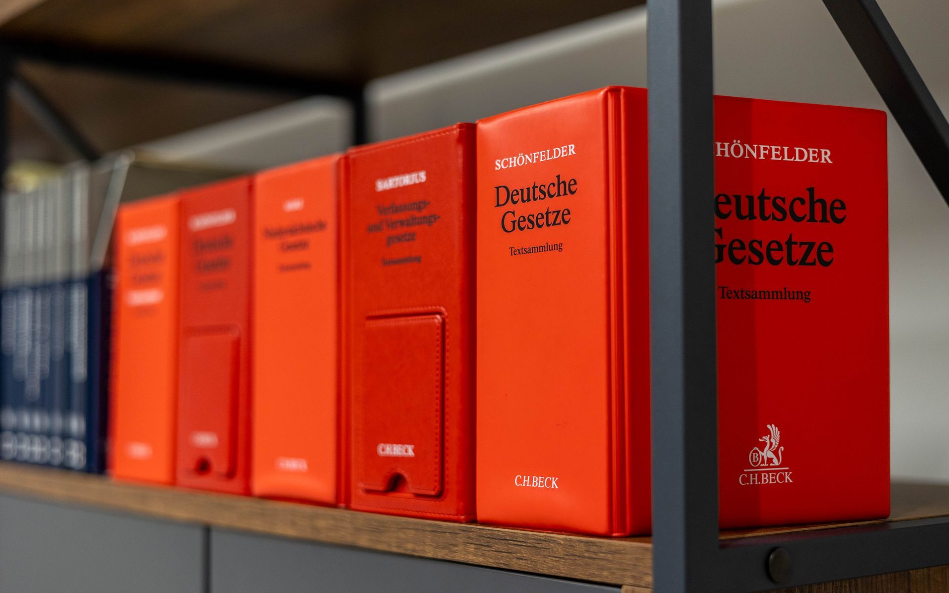 Eine Reihe roter Bücher steht aufgereiht auf einem Regal.