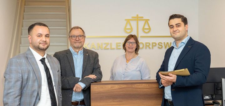 Eine Gruppe von Menschen steht nebeneinander vor einem Tresen.