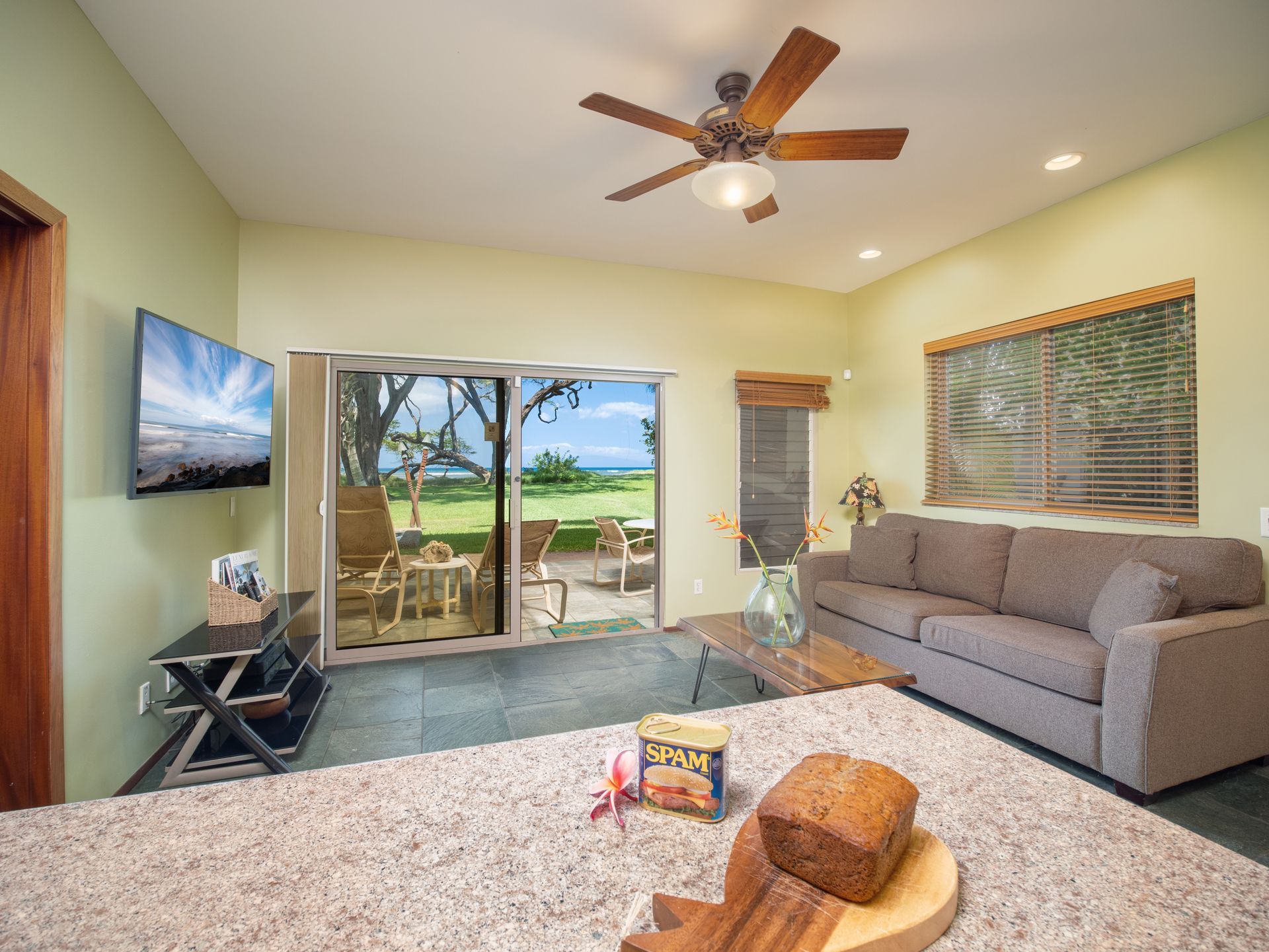 A living room with a couch , television , and a ceiling fan.