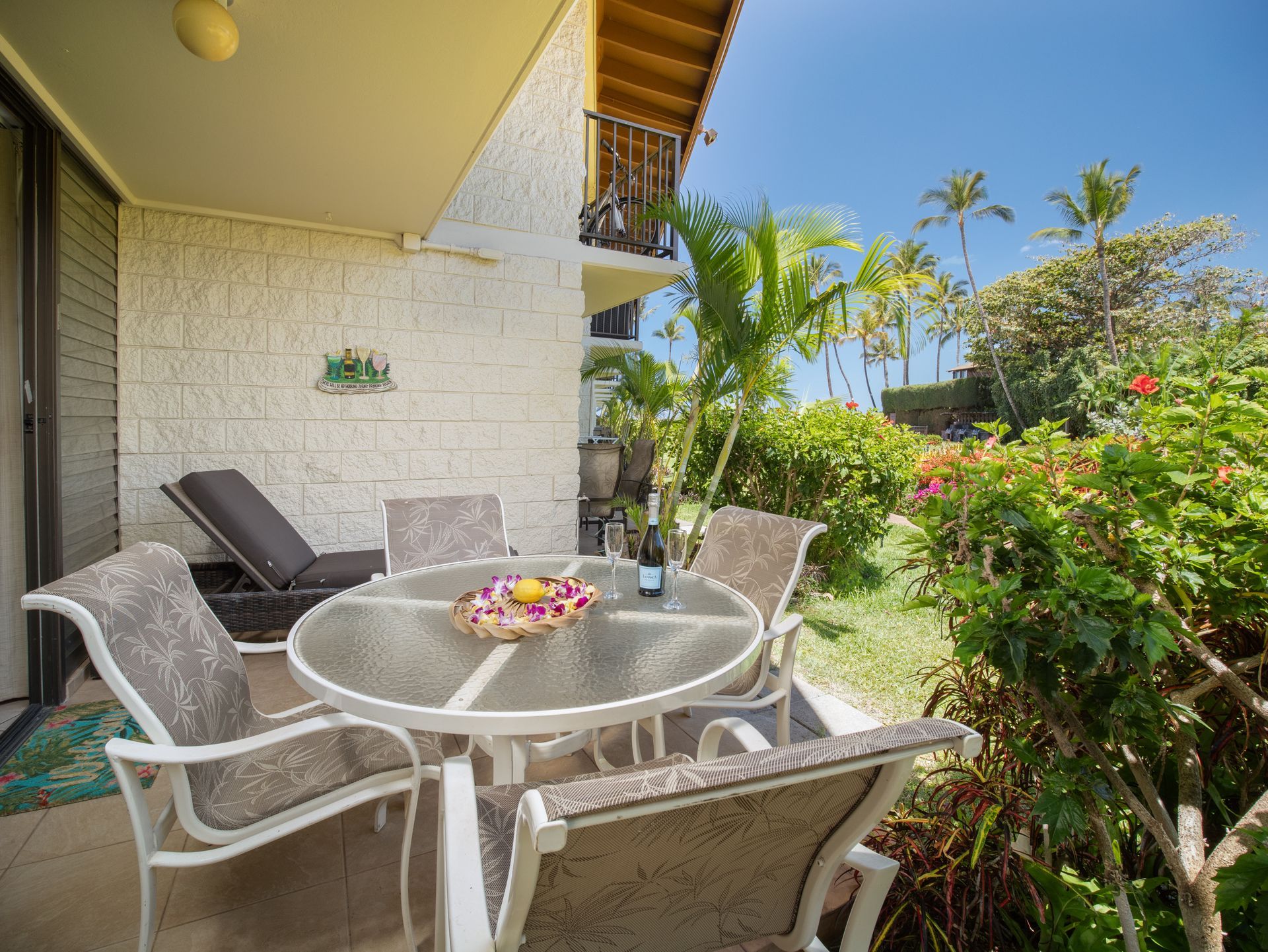 A patio with a table and chairs and a bottle of wine.