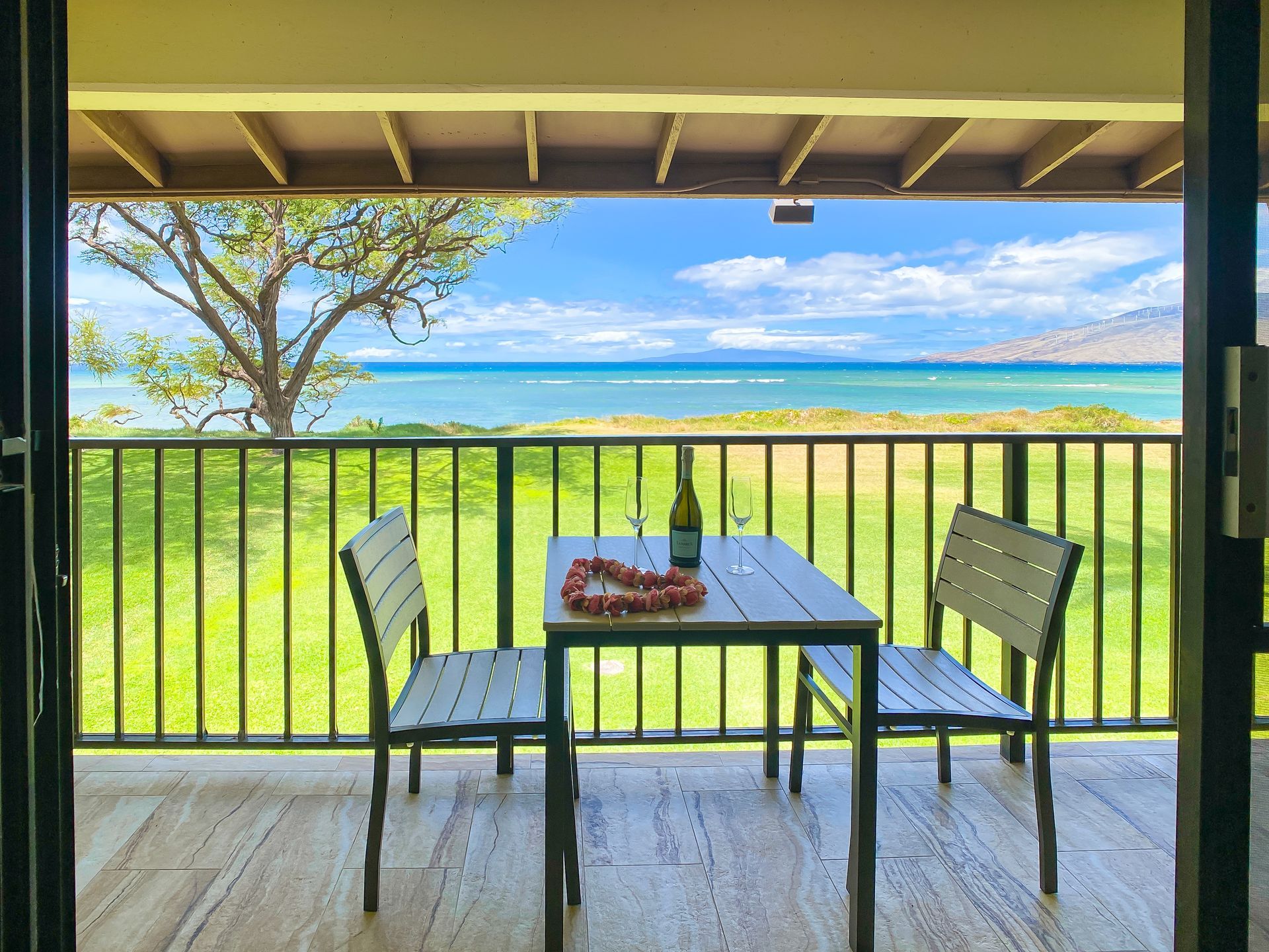 A balcony with a table and chairs overlooking the ocean.