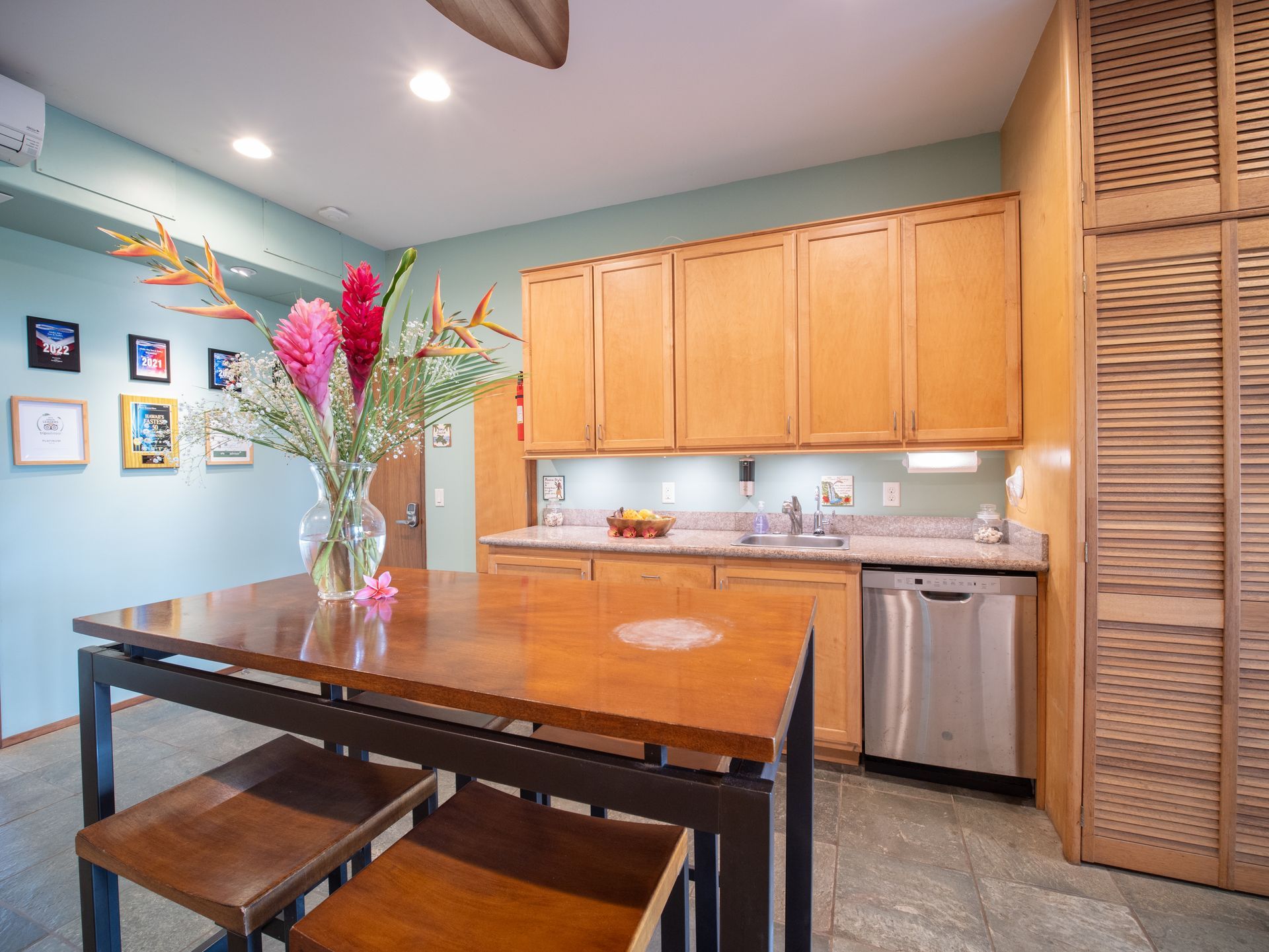 A kitchen with a table and stools and a vase of flowers on it