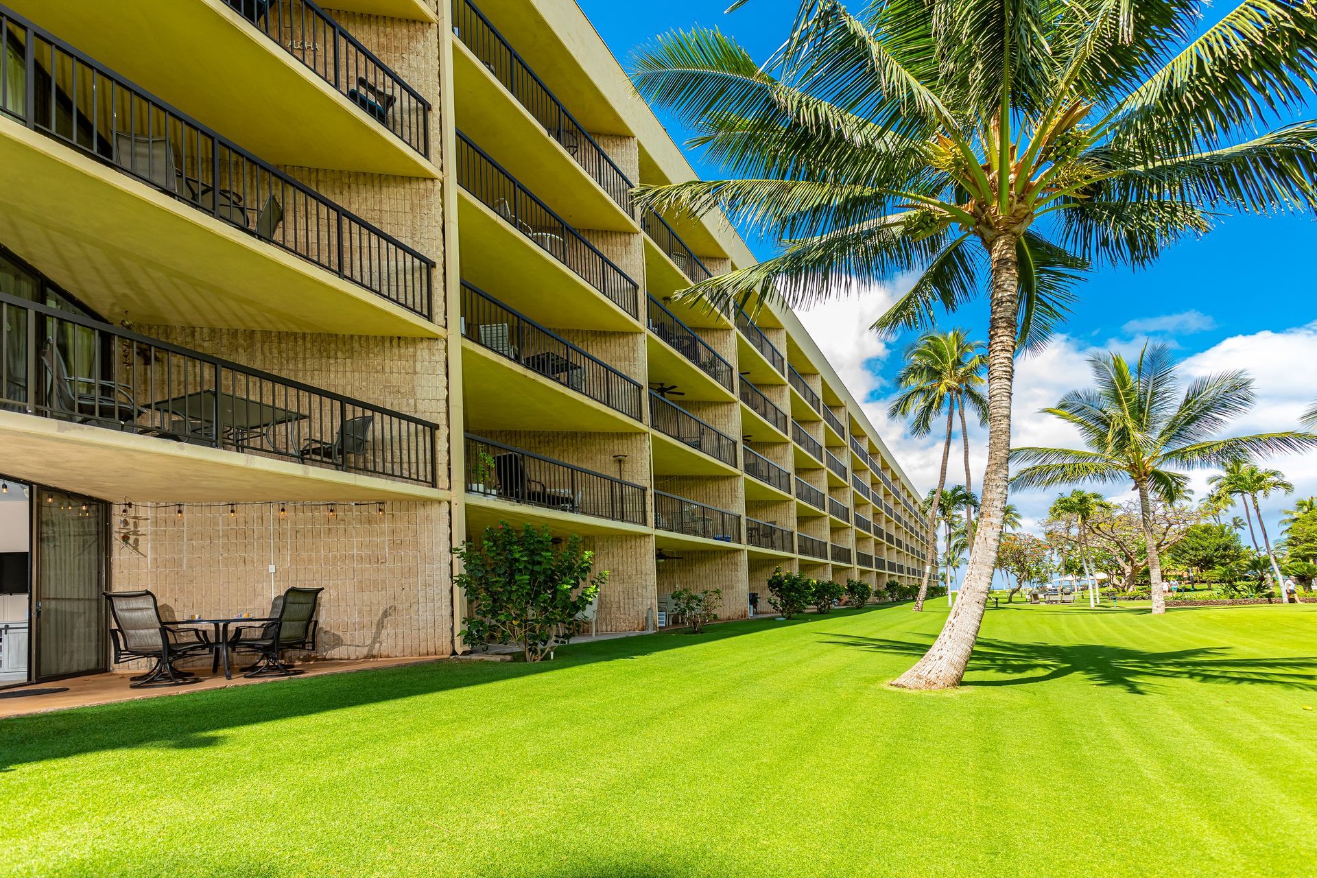 A large building with a lot of balconies and palm trees in front of it.