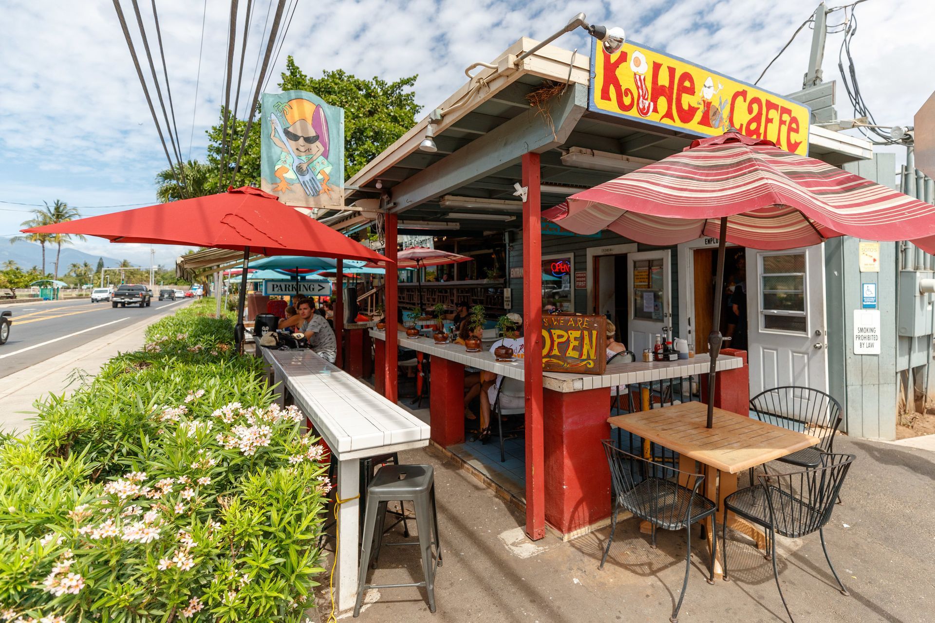 A restaurant with tables and umbrellas on the side of the road.