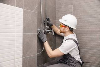 Mitarbeiter von Sa­ni­tär Preiss­ler installiert Dusche