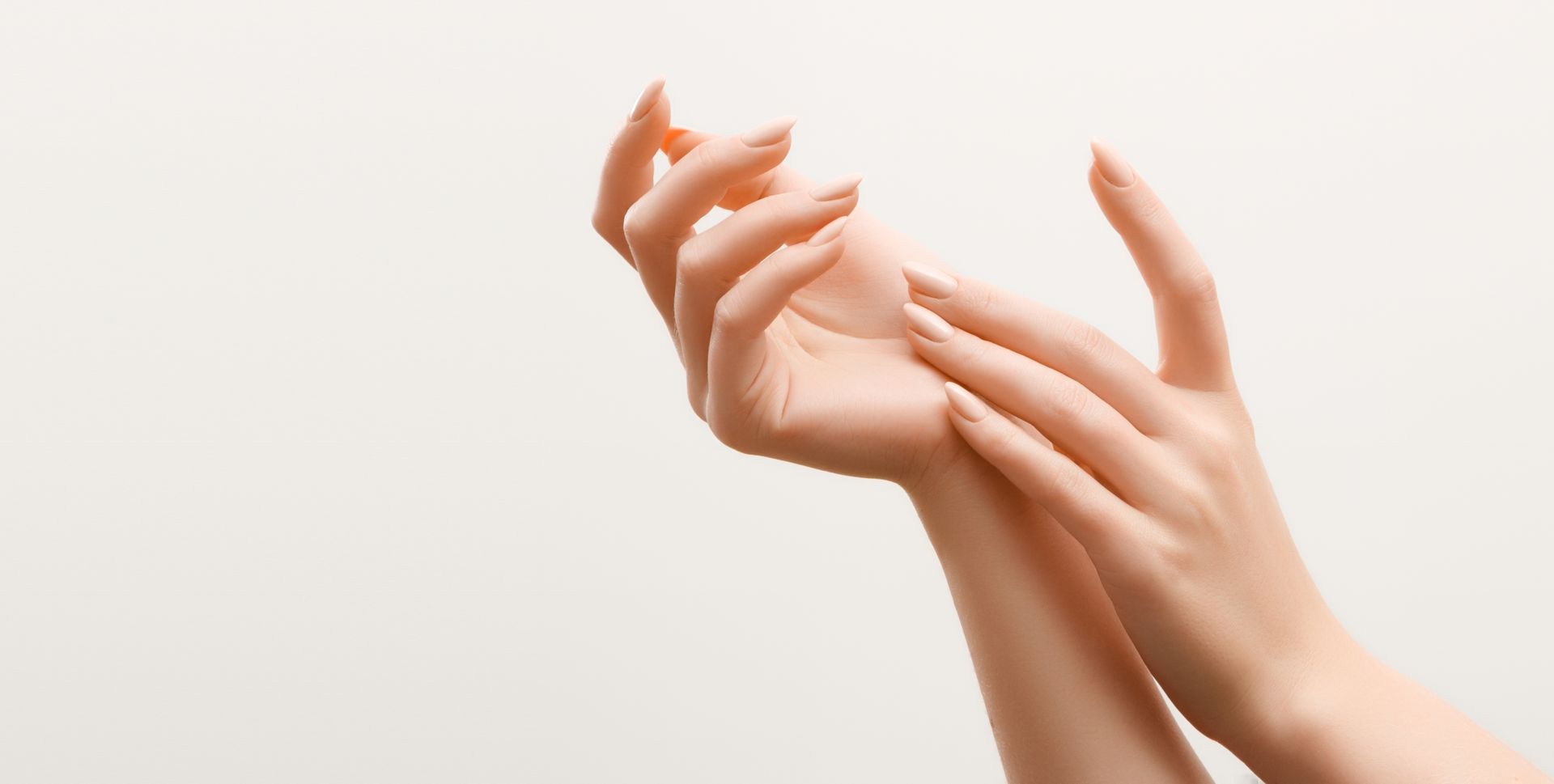 Mains reposant doucement, peau pâle, sur fond blanc.