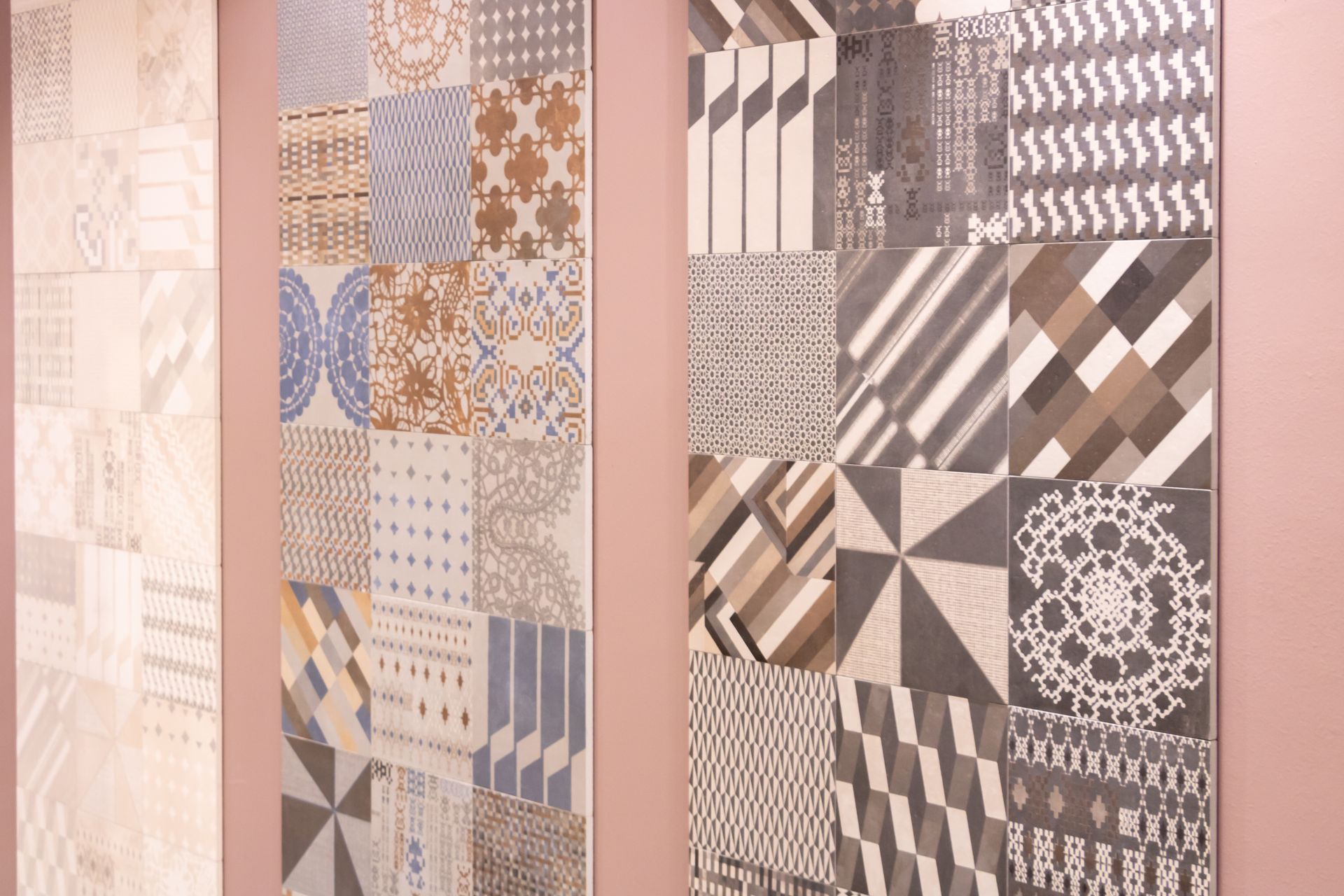 Divers motifs de mosaïque de recouvrement de mur et sol accrochés sur un mur rose.