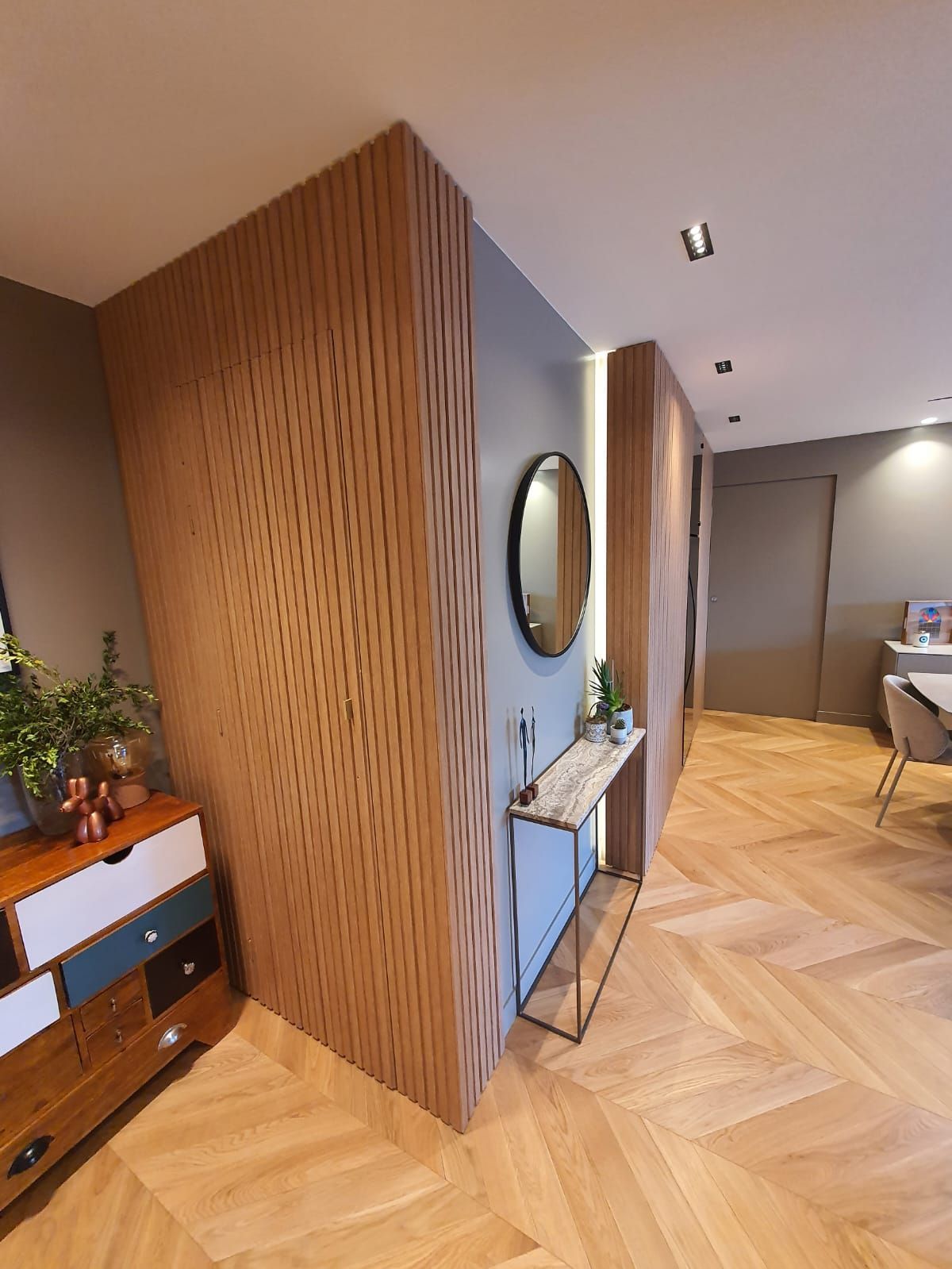 Entrée avec murs recouverts de bois donnant sur un salon.