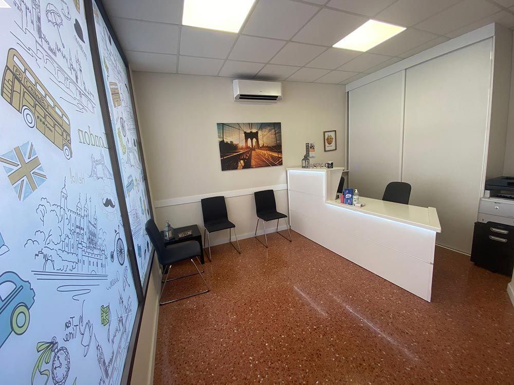 Una sala de espera con un escritorio, sillas y un cuadro en la pared.