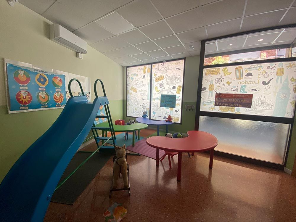 Una habitación infantil con tobogán, mesas y sillas.