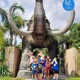 Un grupo de niños de pie frente a una estatua de un elefante.