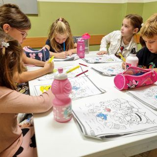 Un grupo de niños están sentados alrededor de una mesa dibujando