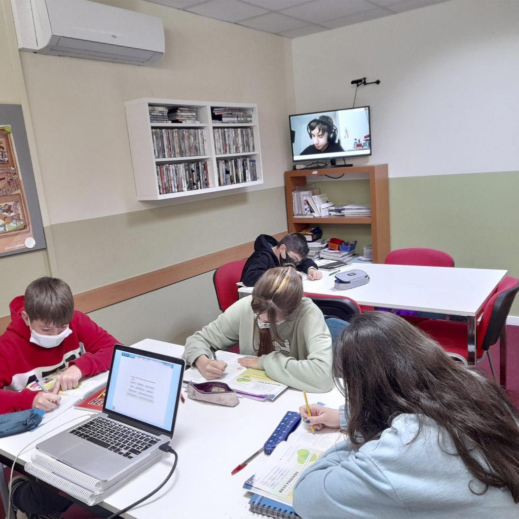 Un grupo de personas está sentado alrededor de una mesa con una computadora portátil encima.