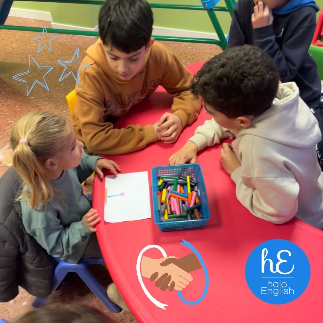 Un grupo de niños está sentado alrededor de una mesa roja con una bandeja de crayones sobre ella.