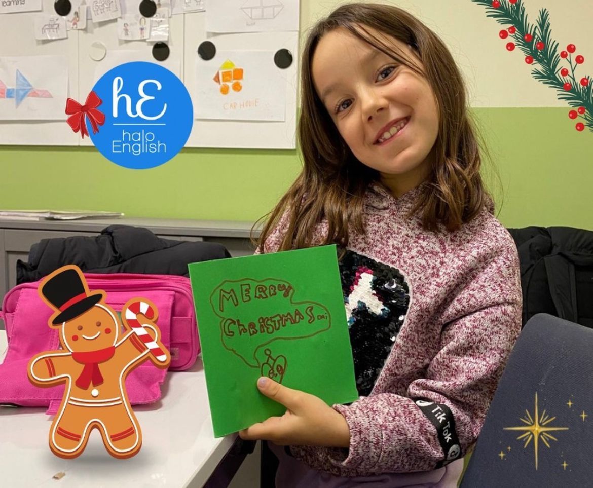 Una niña sostiene una tarjeta navideña con un hombre de jengibre.