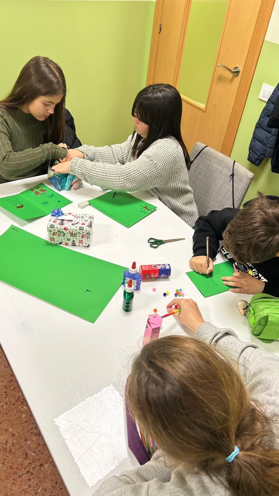 Un grupo de niños están sentados en mesas frente a una pizarra que dice 