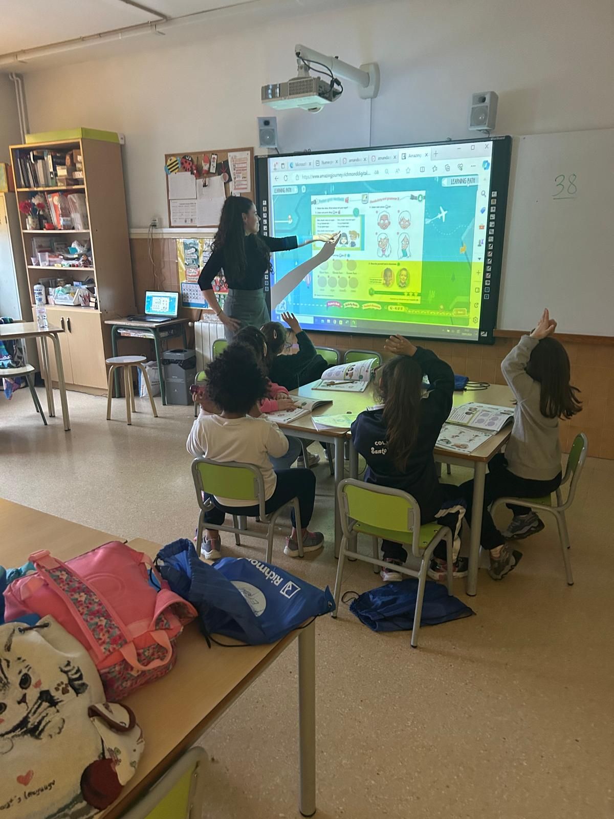 Un grupo de personas están sentadas en mesas con computadoras portátiles en un aula.