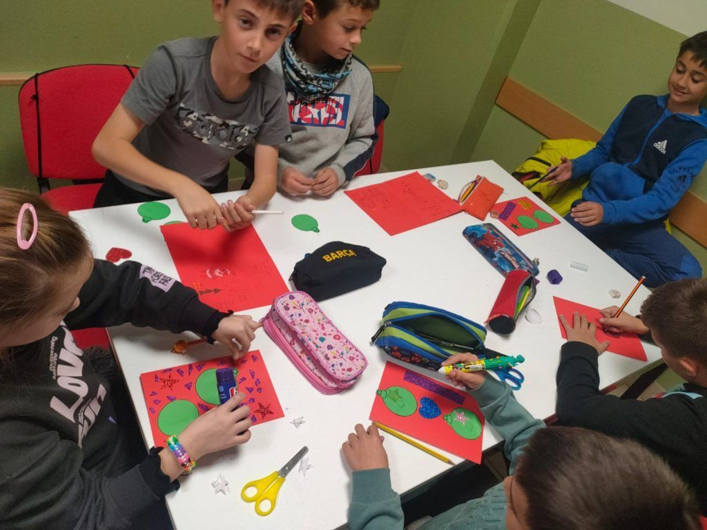 Un grupo de niños están sentados alrededor de una mesa haciendo manualidades.
