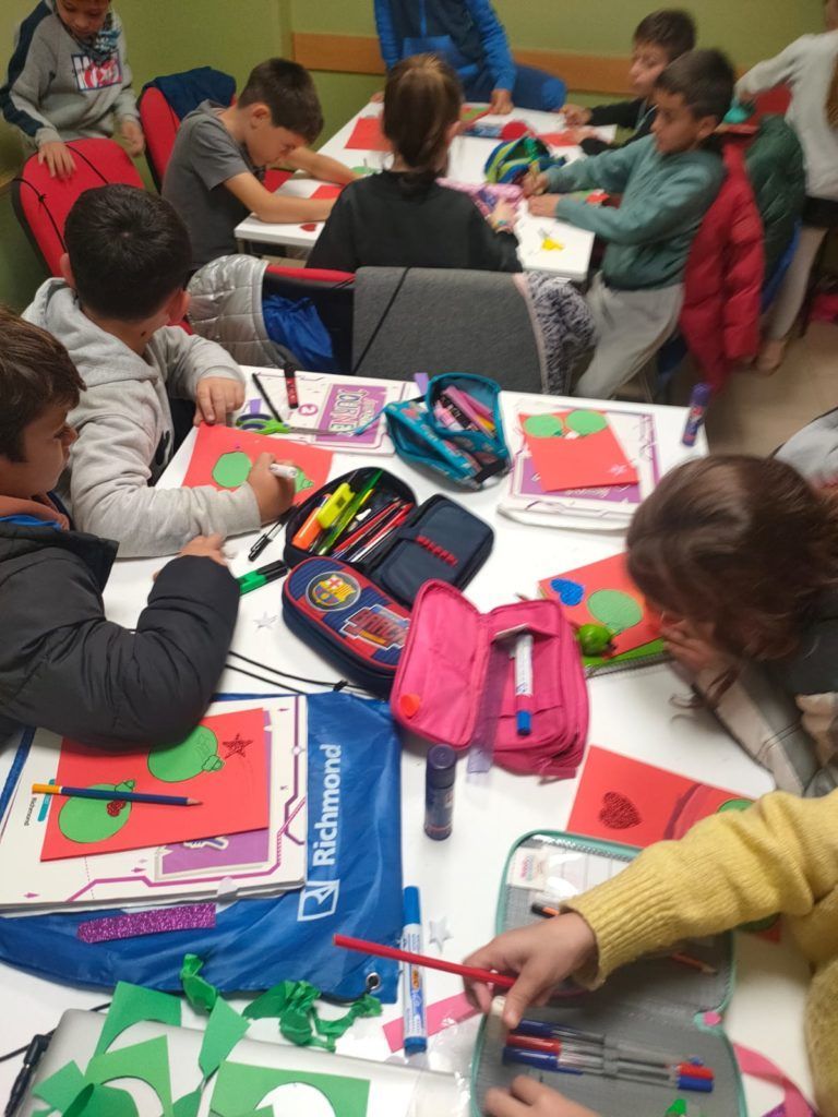 Un grupo de niños están sentados en una mesa haciendo manualidades.