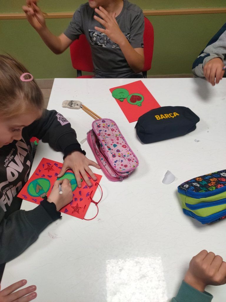 Un grupo de niños están sentados alrededor de una mesa con un estuche que dice 