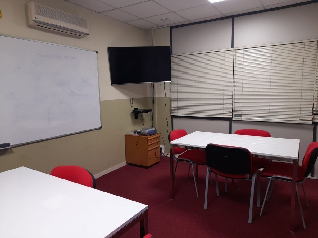 Un aula con mesas y sillas y un televisor de pantalla plana.