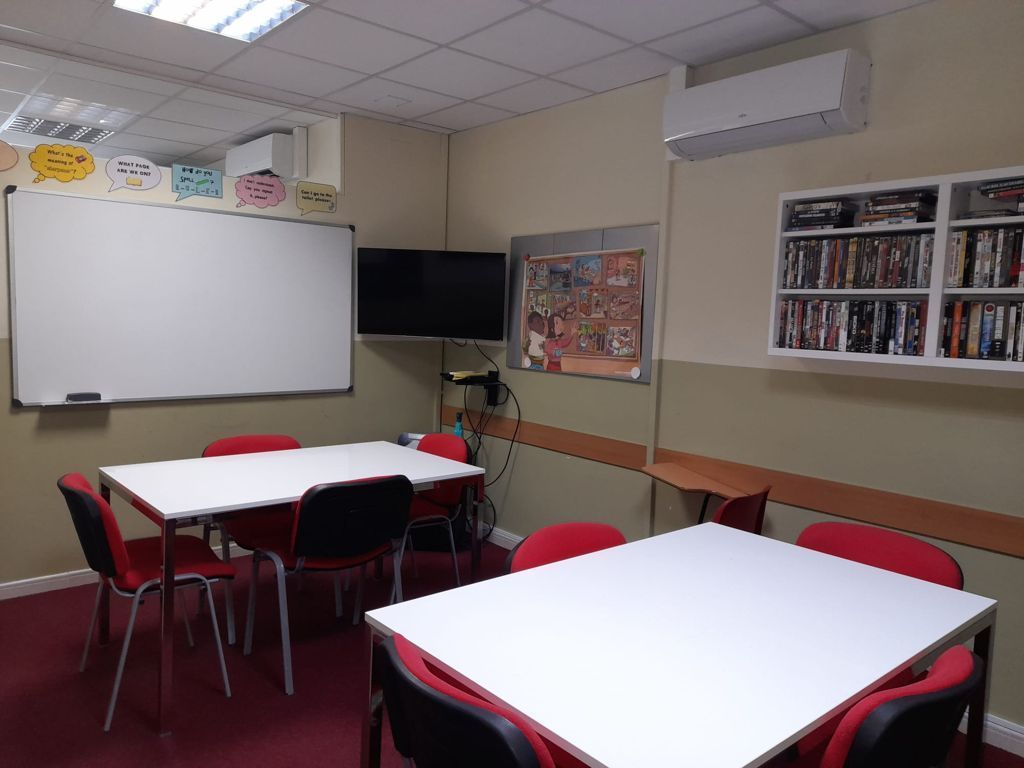 Un aula con mesas y sillas y una pizarra blanca.