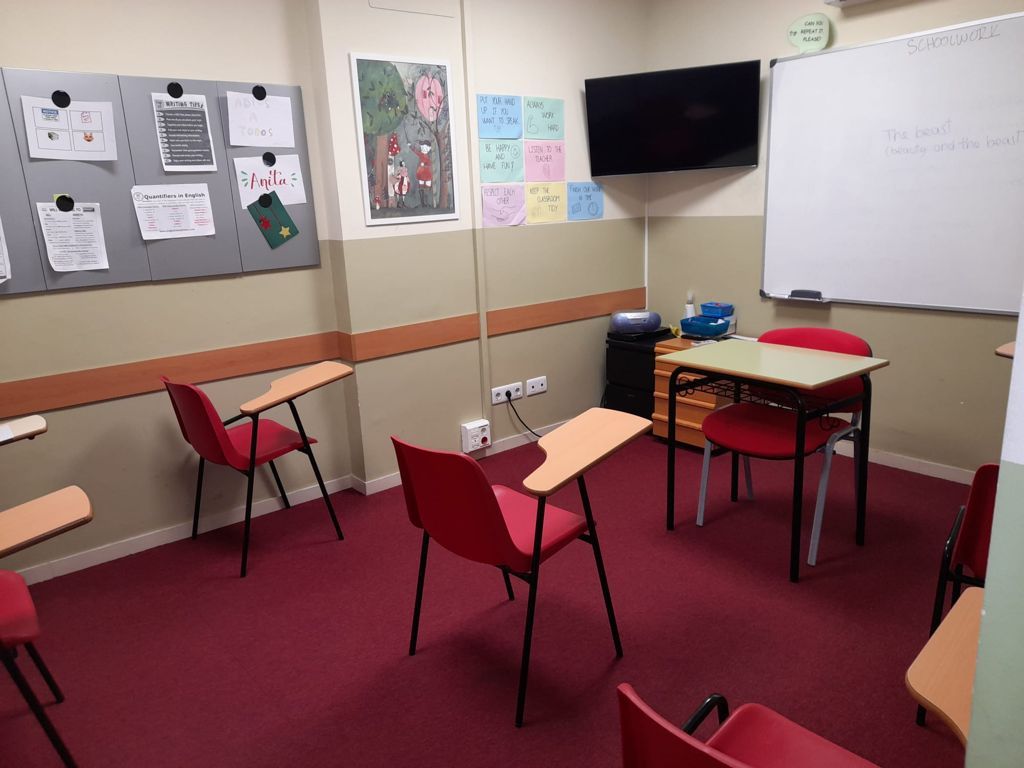 Un aula con mesas y sillas y una pizarra.