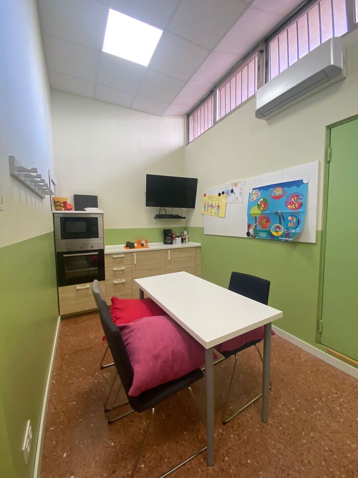 Una habitación con una mesa y sillas y un televisor en la pared.