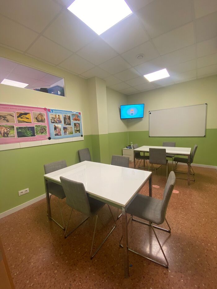 Un aula con una mesa y sillas y una pizarra.