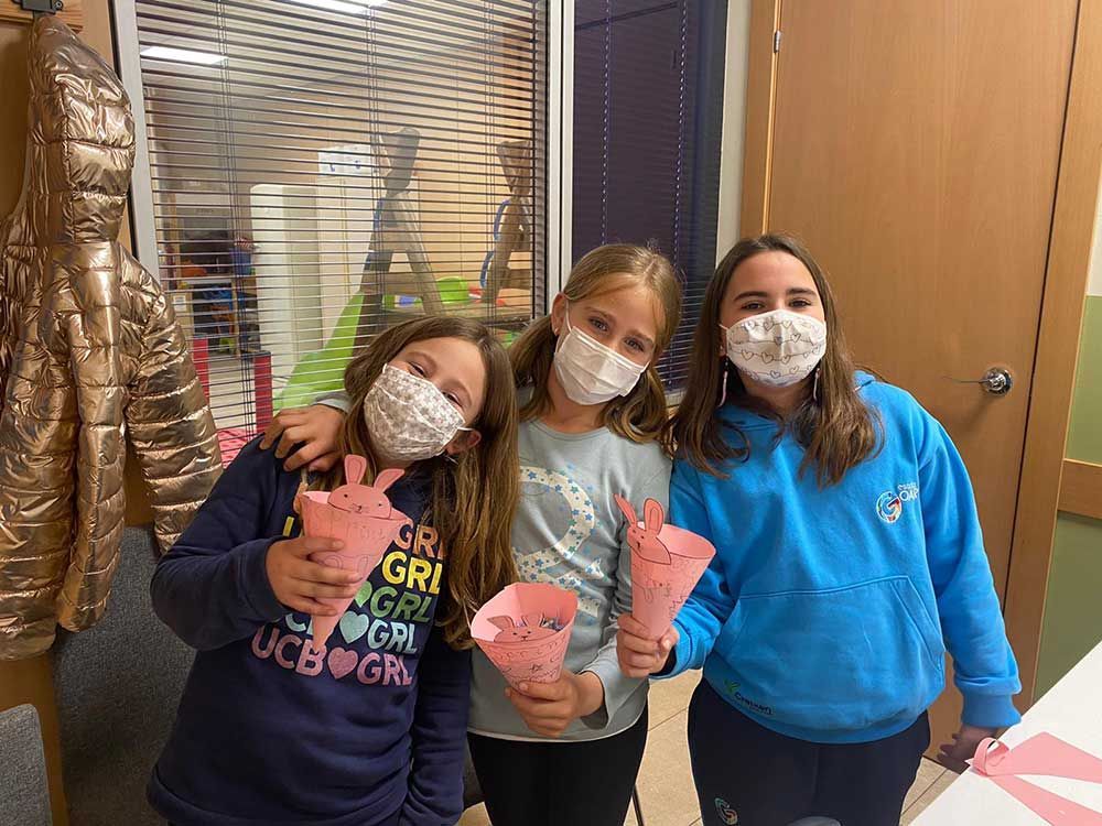 Tres chicas jóvenes con mascarillas posan para una fotografía.