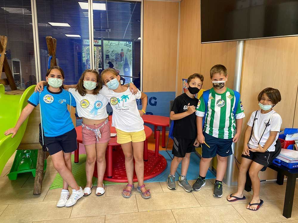 Un grupo de niños que llevan mascarillas están parados uno al lado del otro en una habitación.