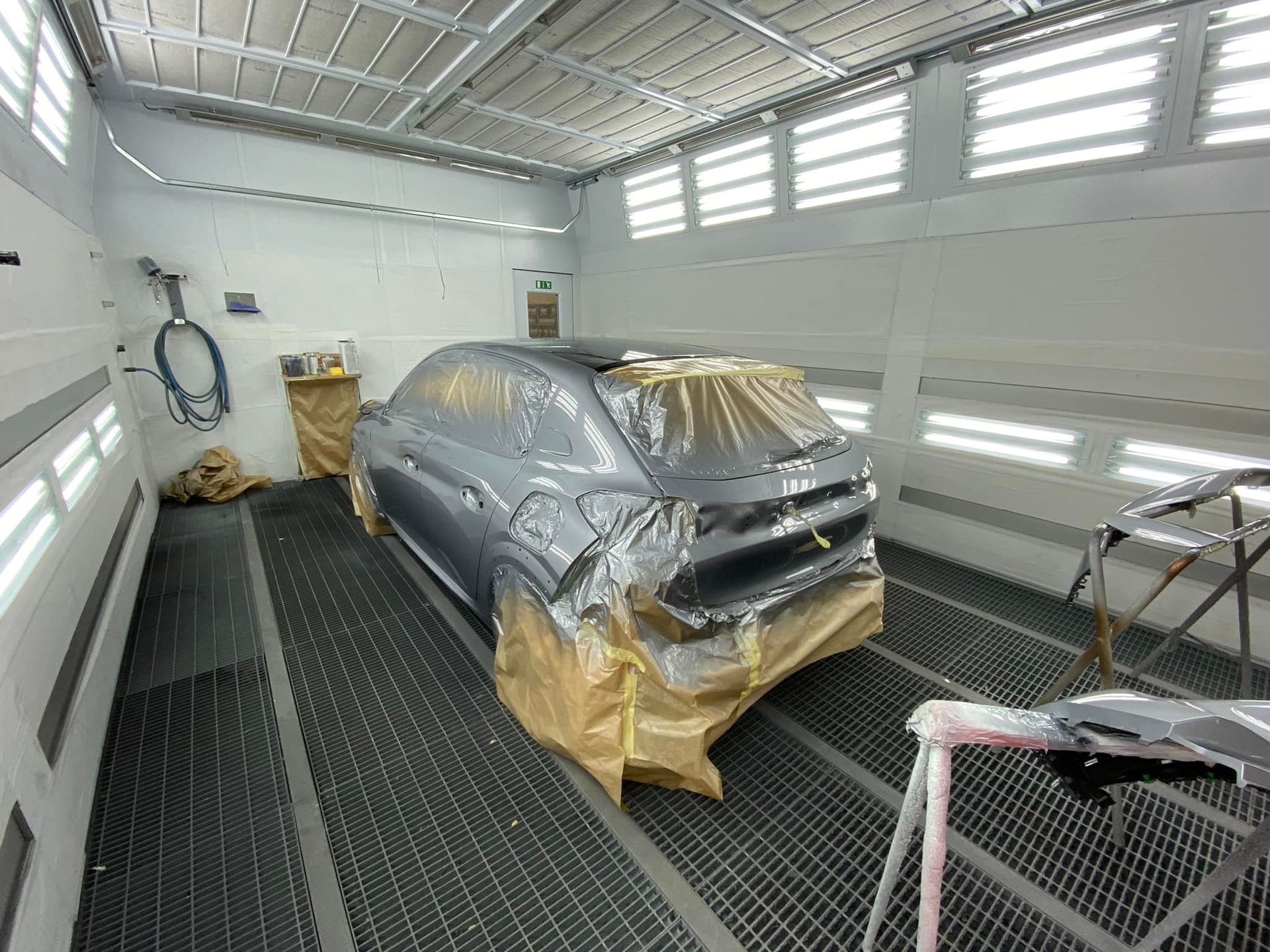 Une voiture grise dans une cabine de peinture.