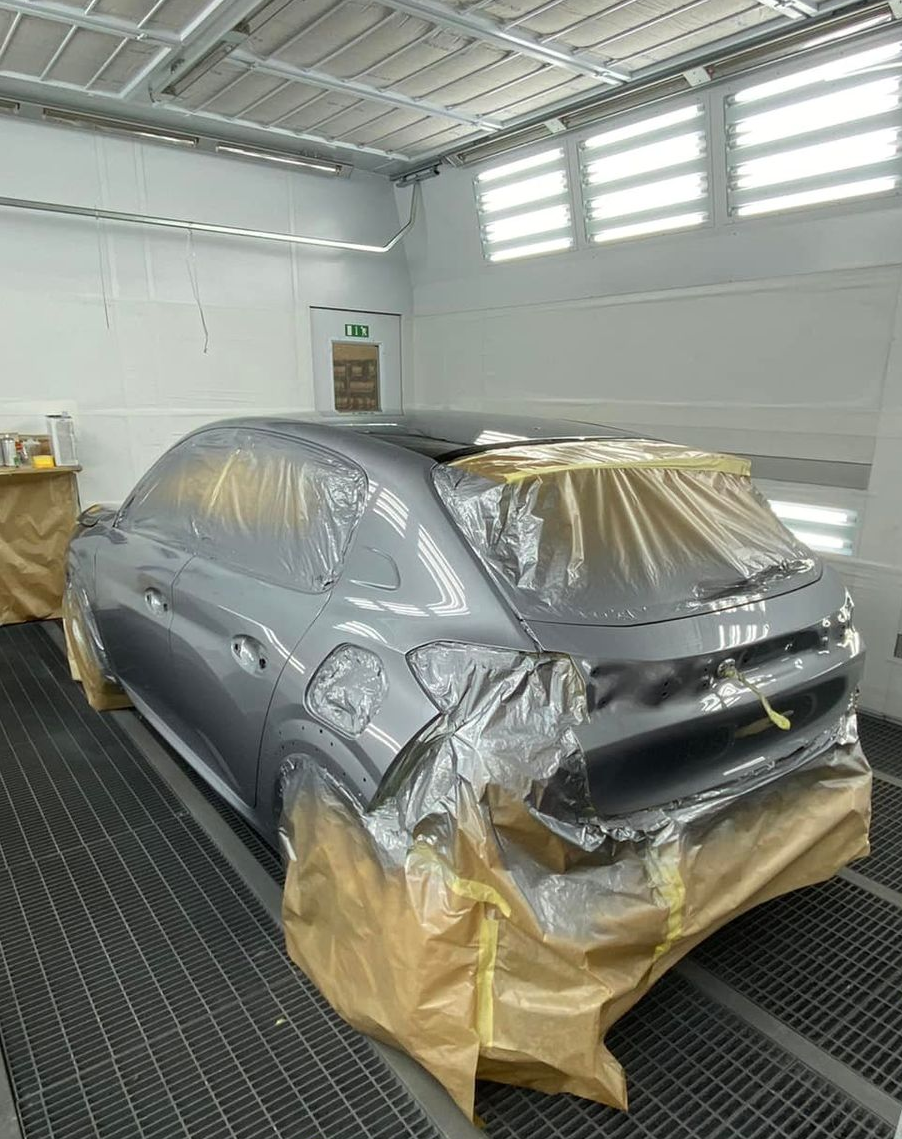 Une voiture grise à l'intérieur d'une cabine de peinture.