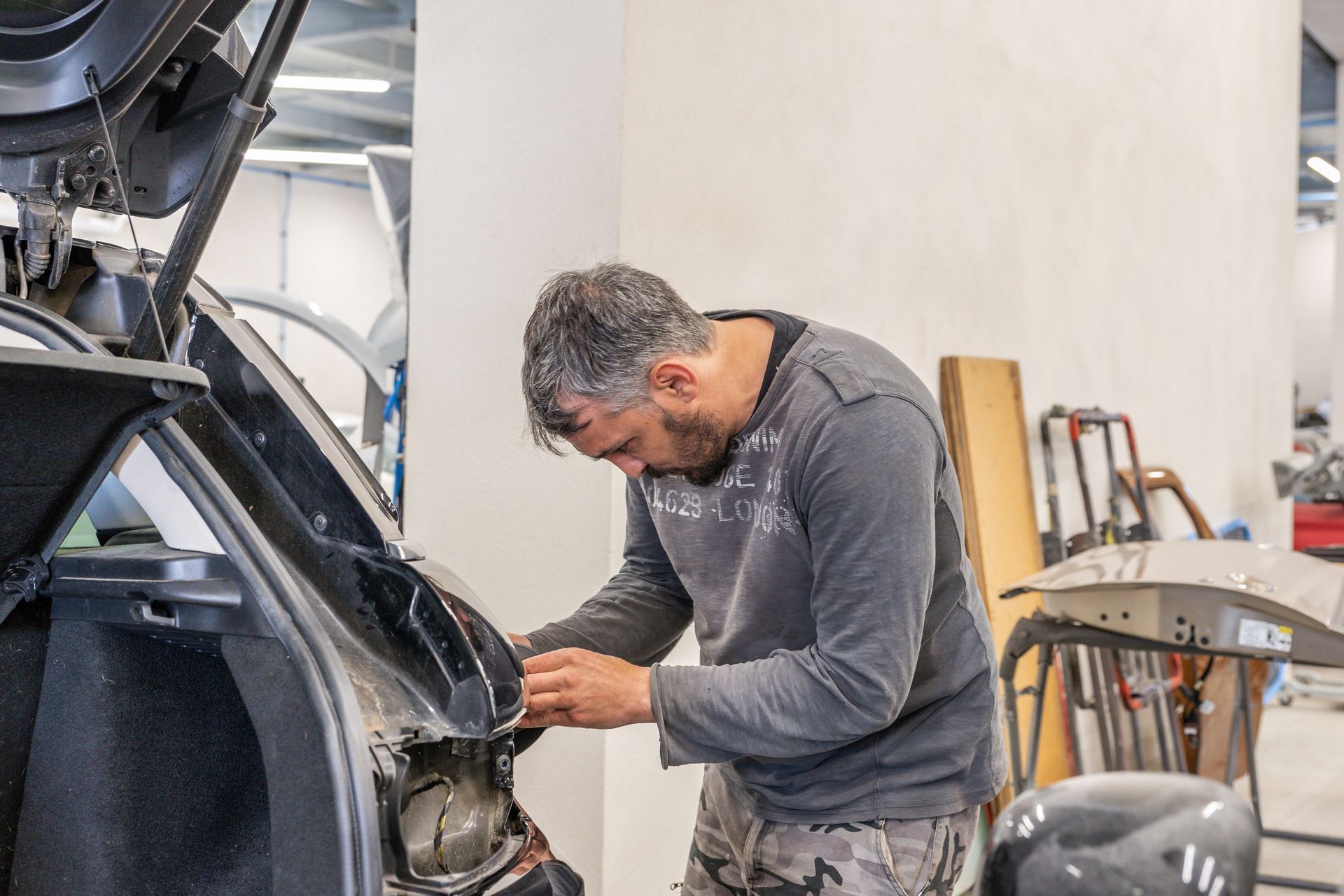 Un technicien travaille sur les feux arrière d'un véhicule dans un atelier de réparation automobile.