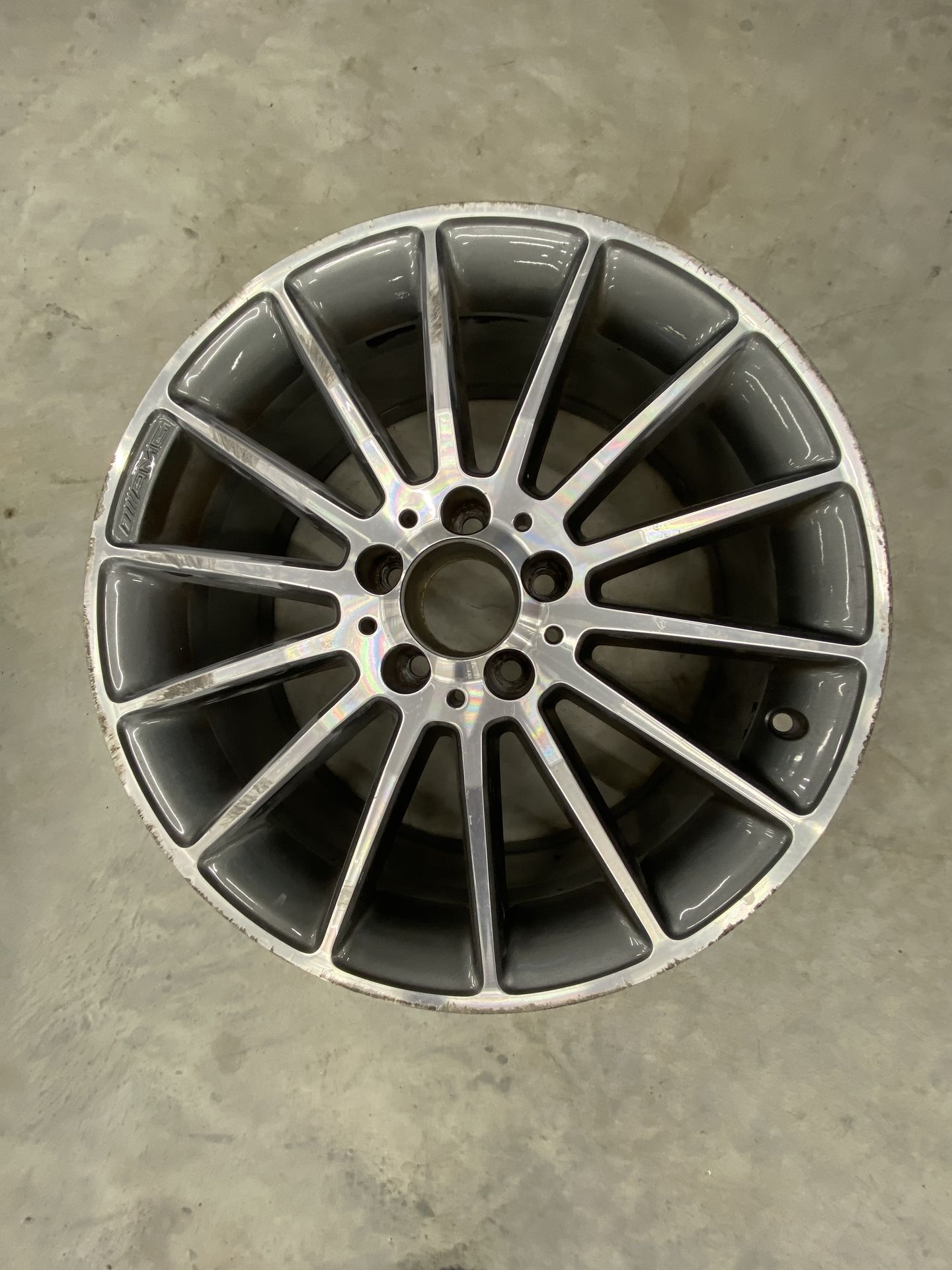 Une jante de voiture en alliage gris posée sur un sol en béton.