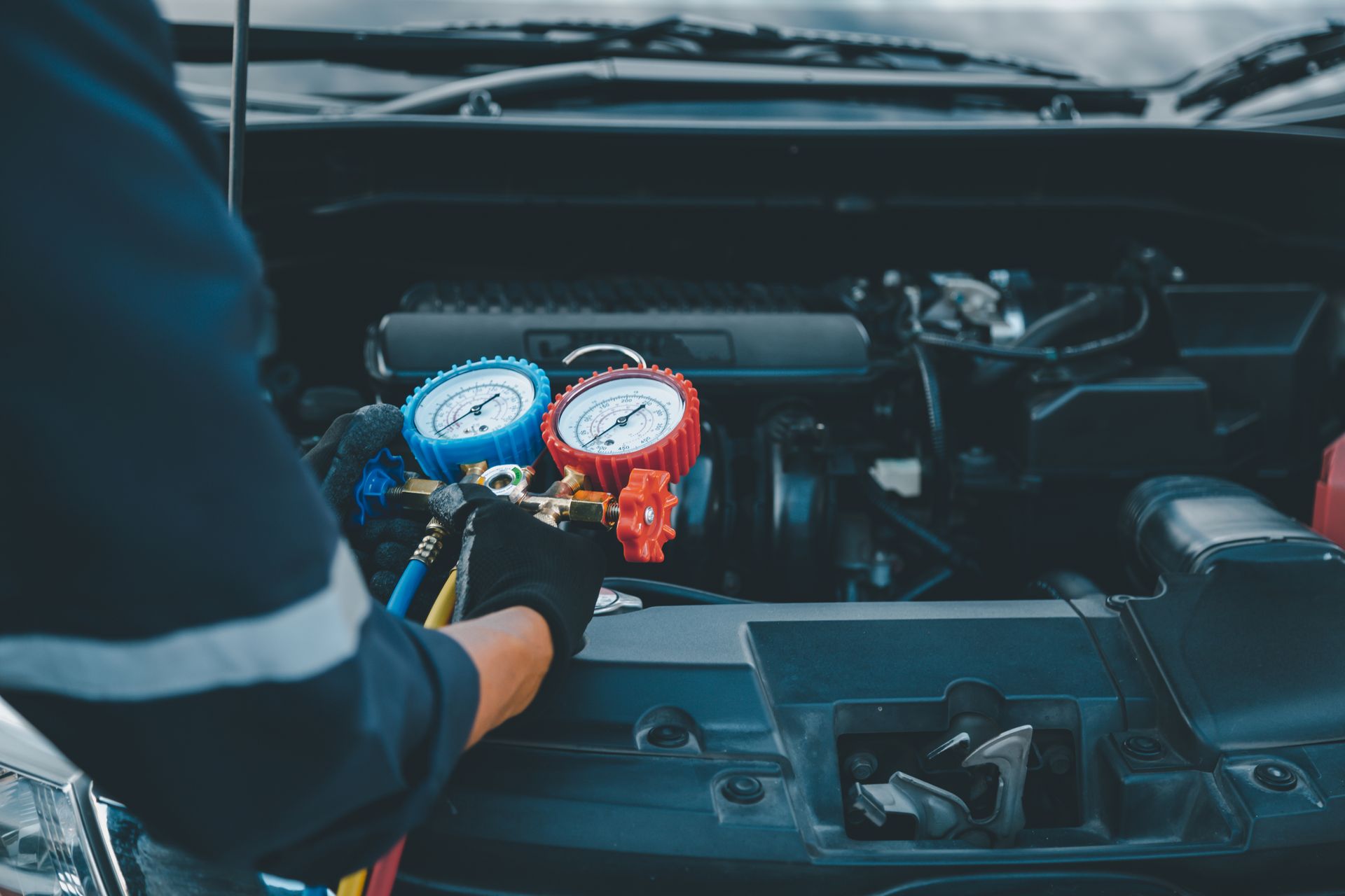 Un mécanicien utilise un manomètre pour compresseur de climatisation automobile afin de tester le système de climatisation.