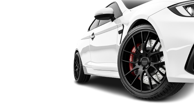 Gros plan sur une voiture de sport blanche, mettant en valeur sa jante en alliage noir.